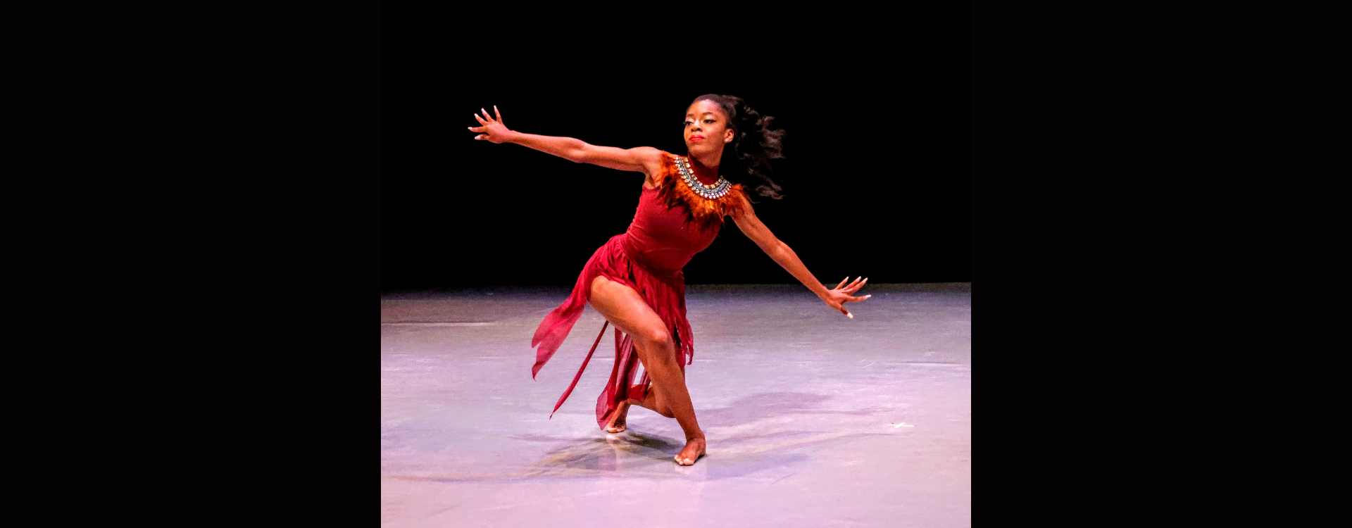 A woman in a red dress is dancing on stage.