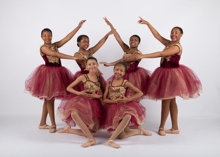 A group of young dancers posing for a photo in a ballet studio.