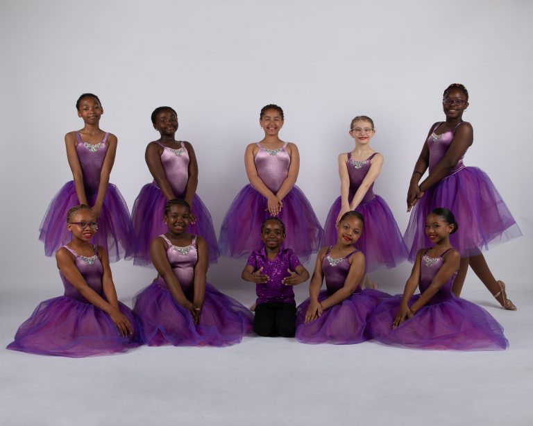 A group of nj ballet dancers in purple tutus posing for a photo.