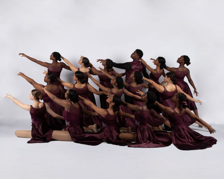 A group of teen dancers at a ballet studio posing for a photo.